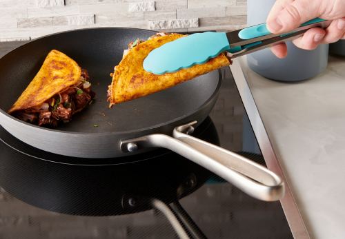 A person cooking in a pan, mixing ingredients in a rich sauce, then frying a tortilla until golden brown, flipping to melt cheese and crisp both sides.